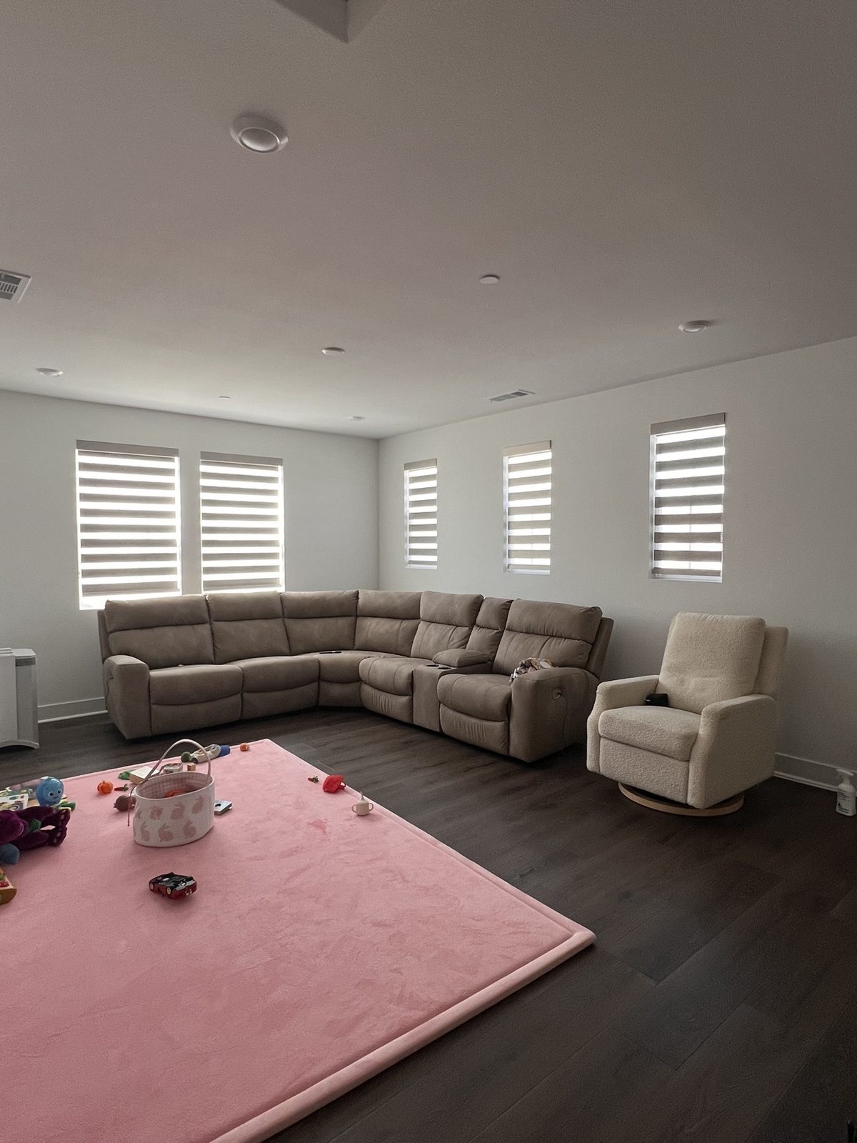 Real ShadeSpot install: blackout zebra shades closed across four windows in a family room with a sectional sofa