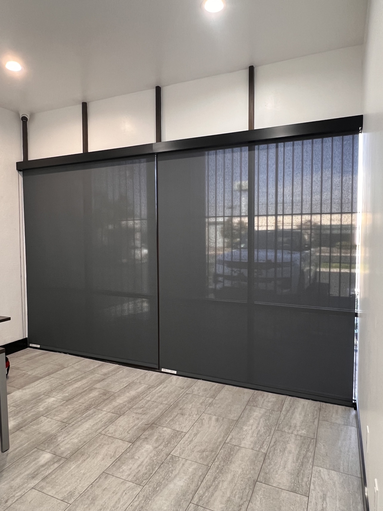 Real ShadeSpot install: charcoal solar screen shades across a commercial storefront glass wall