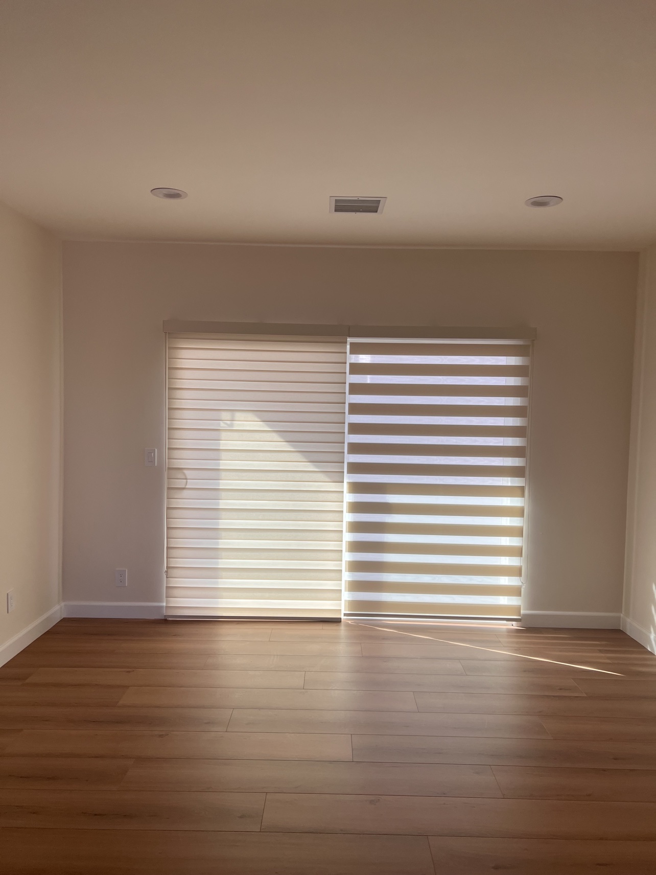 Real ShadeSpot install: light-filtering zebra shades on sliding doors in a wood-floor living room, one side open and one closed