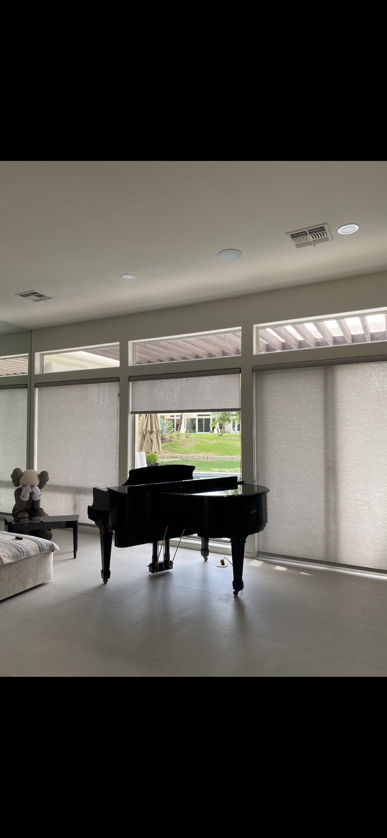 Real ShadeSpot install: light-filtering roller shades on tall glass doors beside a grand piano