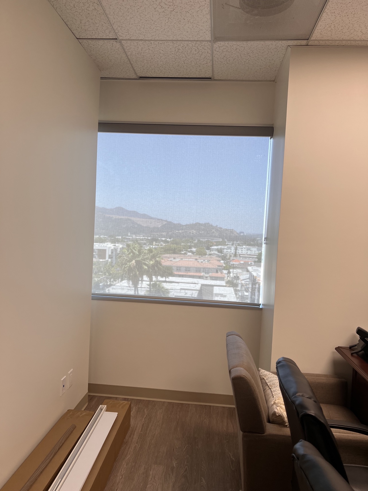 Real ShadeSpot install: solar screen shade on a high-rise office window with the city view visible through the fabric
