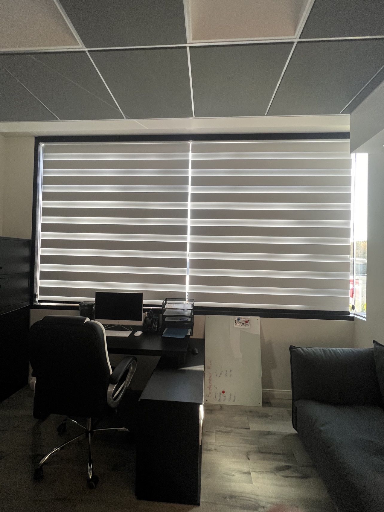Real ShadeSpot install: white zebra shades closed across an office window wall behind a desk
