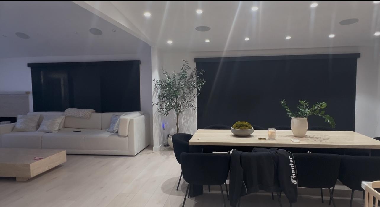 Real ShadeSpot install: charcoal solar screen shades across a wide living room window wall